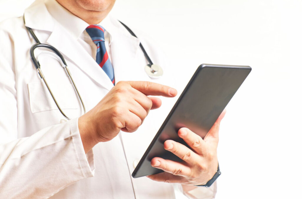 Médico utilizando tablet com informações de pacientes. Imagem ilustrativa para texto LGPD saúde.